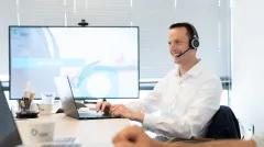 person wearing a headset while working on a laptop in an office