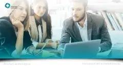 Three people sat around a laptop analyzing the screen.